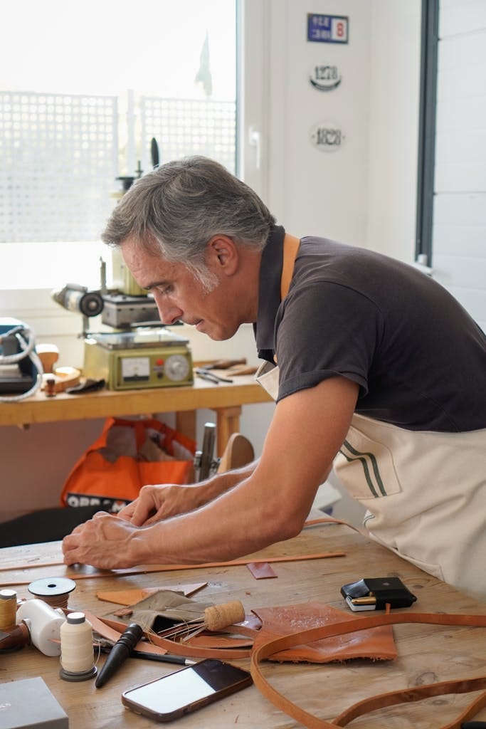 Skilled artisan crafting leather goods in a sunlit Madrid workshop.